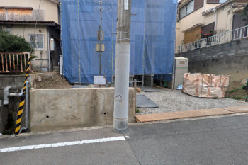 高槻市の外構着工前の敷地の様子です。高槻の住宅地は山側の場合も多く傾斜地で道路と建物のGLが同等でないことがあります。こちらは隣地をご覧いただけるように手前の擁壁の高さ程度建物の基礎が高くなっています。道路から玄関までなだらかにつなぐエクステリアにする必要があります