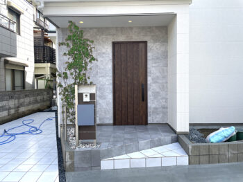 守口市の外構玄関まわりの様子ですオリジナルの門柱を製作し一番上に樹脂の上に直接お名前を彫った表札パネルを取付けシンプルで美しいエントランスになっています